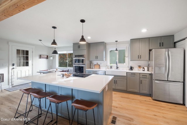 kitchen with stainless steel appliances, gray cabinetry, visible vents, and a sink