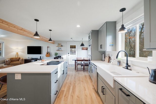 kitchen with stainless steel dishwasher, a center island, light countertops, black electric stovetop, and gray cabinetry