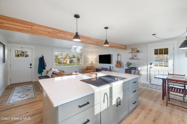 kitchen with light wood-style flooring, pendant lighting, a healthy amount of sunlight, and light countertops
