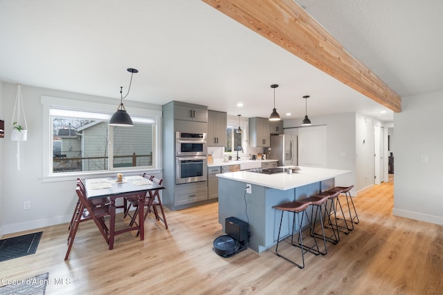 kitchen featuring light countertops, appliances with stainless steel finishes, beamed ceiling, and gray cabinetry