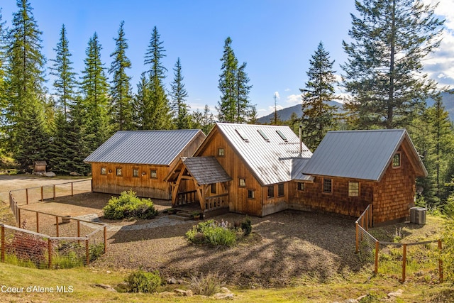 back of house featuring a mountain view, fence, metal roof, and a standing seam roof