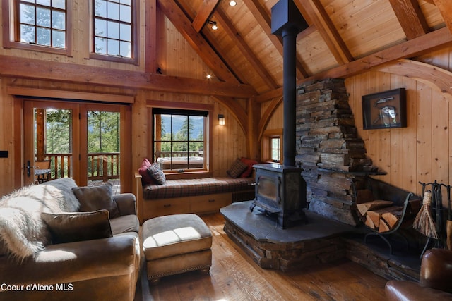 living room featuring wood walls, a wood stove, and hardwood / wood-style flooring