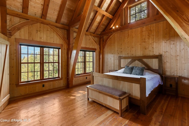 bedroom with beamed ceiling, high vaulted ceiling, wooden ceiling, wood walls, and hardwood / wood-style flooring