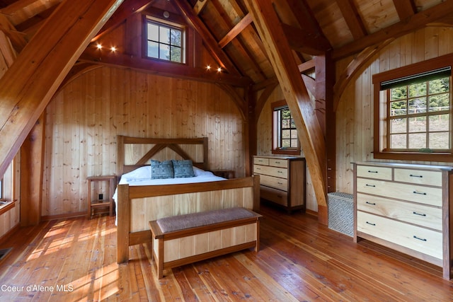 bedroom with wooden walls, multiple windows, and hardwood / wood-style flooring