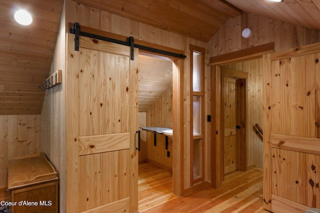interior space with wood walls, a barn door, and lofted ceiling