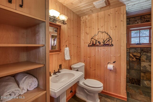 bathroom featuring toilet, wood ceiling, wood walls, and visible vents