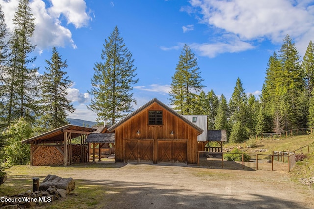 view of barn featuring driveway and fence