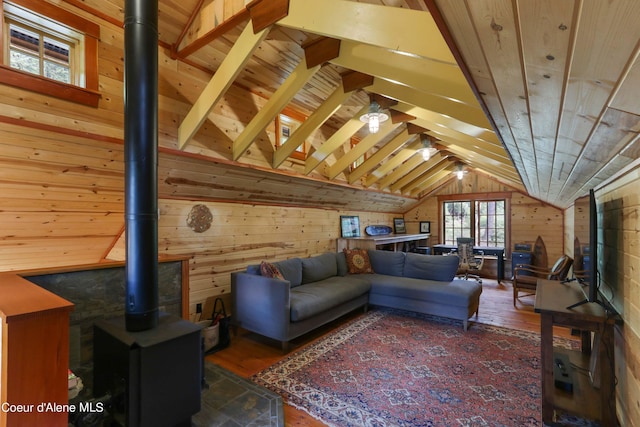 living room with wood walls, a wood stove, wood ceiling, vaulted ceiling with beams, and wood finished floors