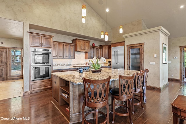 1122 S Four Winds Rd, Coeur Dalene, ID 83814 - kitchen with light stone countertops, open shelves, appliances with stainless steel finishes, a large island, and dark wood-style floors