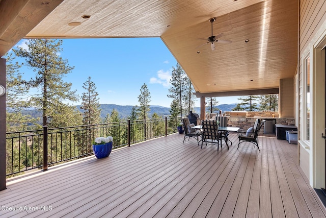 1122 S Four Winds Rd, Coeur Dalene, ID 83814 - wooden terrace featuring outdoor dining area, a mountain view, and a ceiling fan