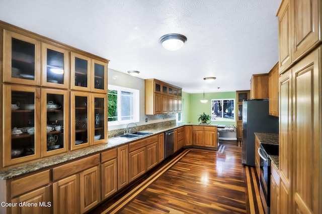 234 Stoneridge Rd, Blanchard, ID 83804 - kitchen featuring brown cabinetry, a peninsula, appliances with stainless steel finishes, a sink, and dark wood-style floors