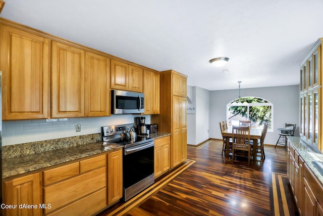 234 Stoneridge Rd, Blanchard, ID 83804 - kitchen with dark stone countertops, appliances with stainless steel finishes, dark wood-style floors, and brown cabinets