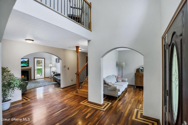 234 Stoneridge Rd, Blanchard, ID 83804 - foyer featuring arched walkways, a towering ceiling, a lit fireplace, wood finished floors, and stairs