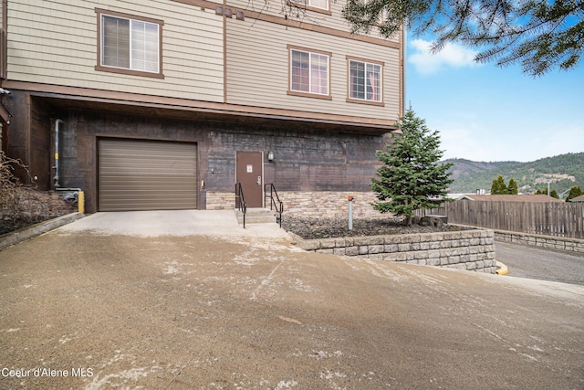 view of front of property featuring a mountain view, fence, a garage, and driveway