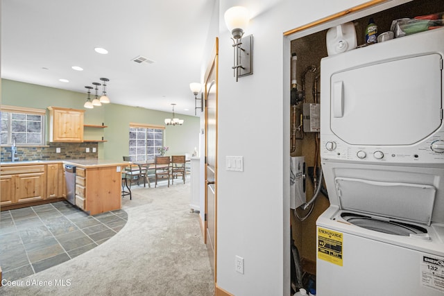 laundry room featuring carpet flooring, visible vents, stacked washer / drying machine, laundry area, and a sink