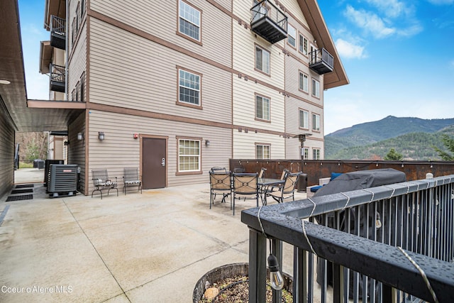 exterior space with a mountain view, outdoor dining space, cooling unit, and a balcony