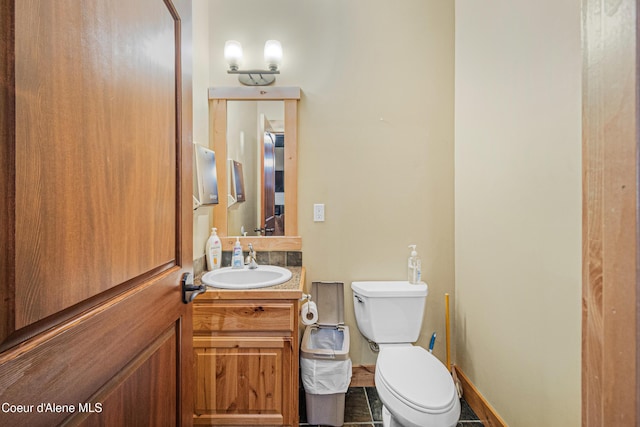 bathroom with toilet, vanity, and baseboards