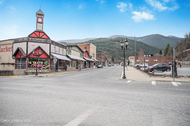 view of road with sidewalks, street lights, a mountain view, and curbs