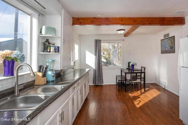 kitchen with beamed ceiling, visible vents, freestanding refrigerator, and a sink