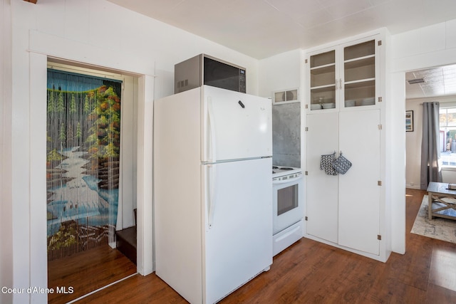 kitchen featuring dark wood-type flooring, visible vents, white appliances, and glass insert cabinets