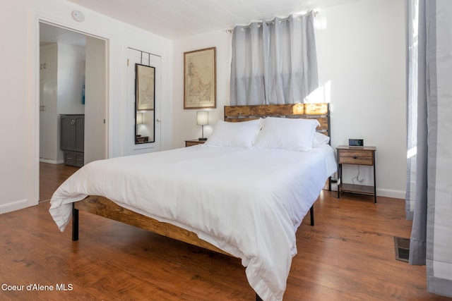 bedroom featuring wood finished floors, baseboards, and visible vents