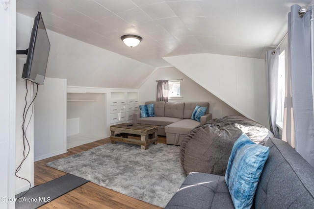 living area with wood finished floors, built in shelves, and lofted ceiling