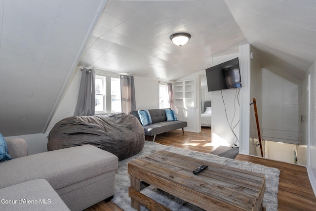 living room featuring wood finished floors, lofted ceiling, and built in features
