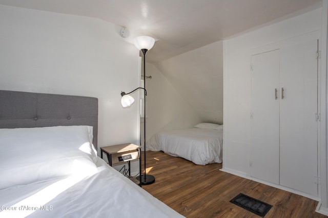 bedroom with wood finished floors, visible vents, and vaulted ceiling