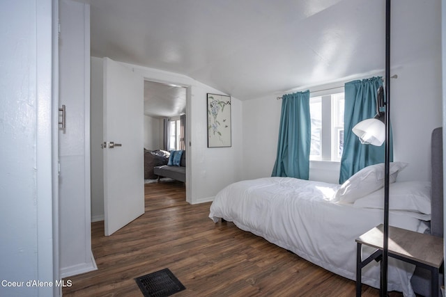 bedroom with visible vents, dark wood-style flooring, multiple windows, and lofted ceiling