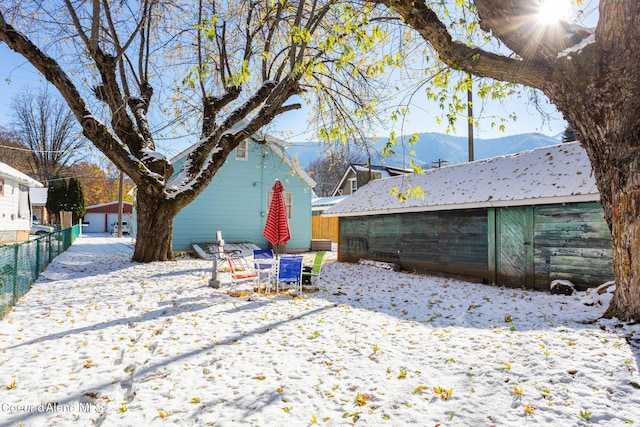 snow covered property with an outbuilding, a mountain view, and fence
