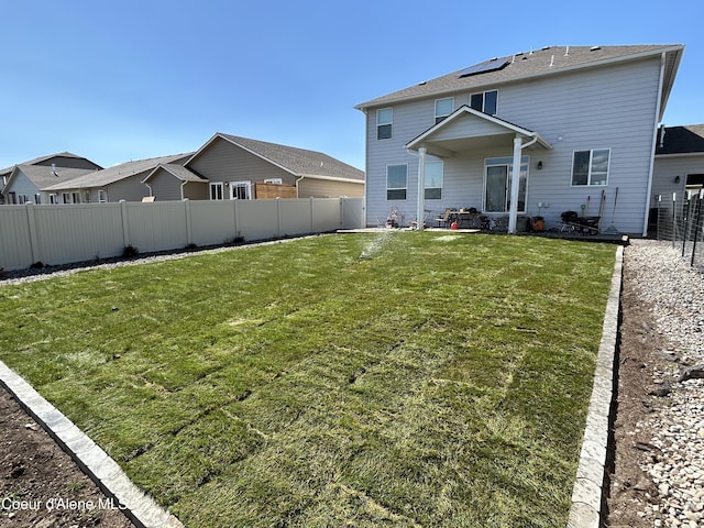 rear view of property featuring a fenced backyard and a lawn