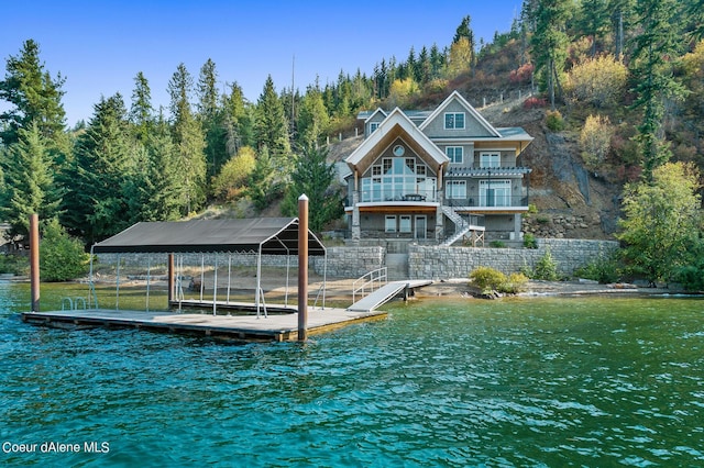 dock area with a water view, stairway, and a wooded view