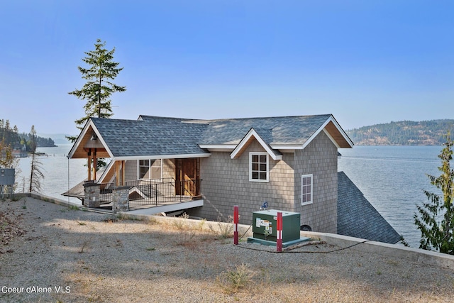 rear view of property featuring a water view and roof with shingles