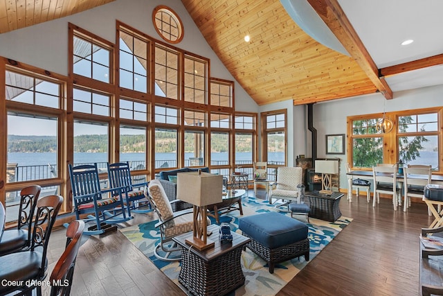 living room featuring a water view, a wood stove, hardwood / wood-style flooring, beamed ceiling, and high vaulted ceiling