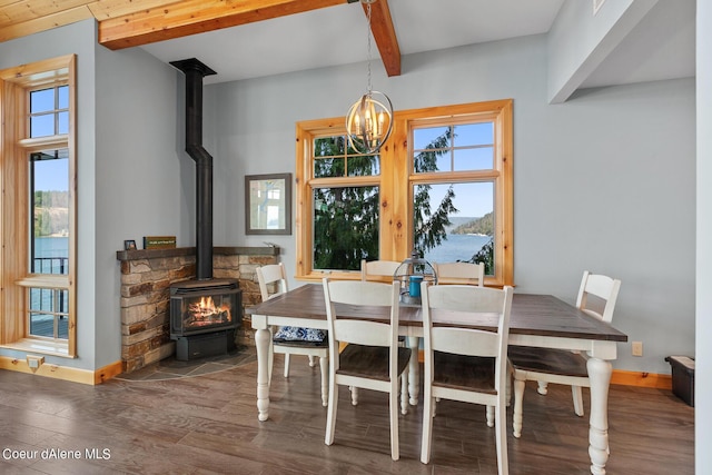 dining space with wood finished floors, a wood stove, beamed ceiling, and baseboards