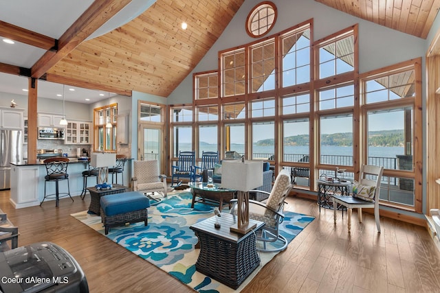 interior space with a water view, beam ceiling, high vaulted ceiling, and hardwood / wood-style flooring