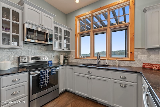 kitchen with a sink, tasteful backsplash, appliances with stainless steel finishes, and dark countertops
