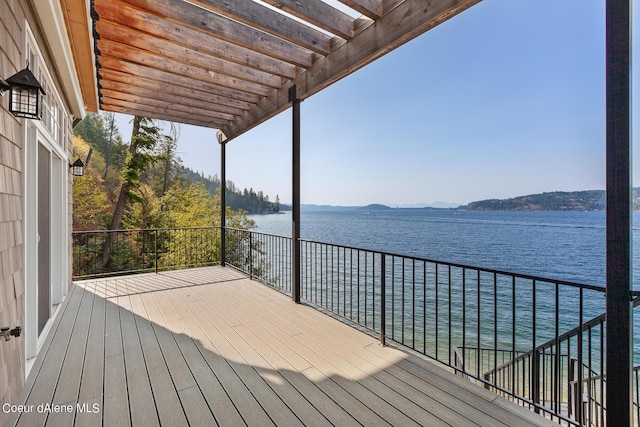 wooden deck with a water and mountain view and a pergola