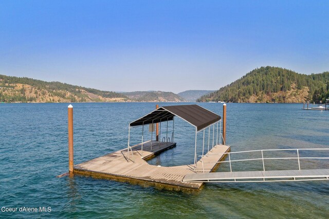 dock area with a view of trees and a water and mountain view