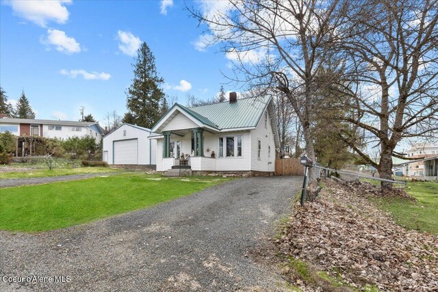 315 S 5th St, Saint Maries, ID 83861 - view of front facade featuring a chimney, a detached garage, driveway, a front lawn, and metal roof