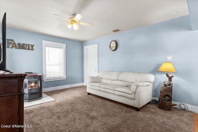 315 S 5th St, Saint Maries, ID 83861 - carpeted living room with visible vents, a wood stove, a ceiling fan, and baseboards