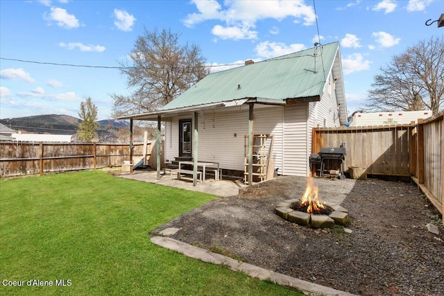 315 S 5th St, Saint Maries, ID 83861 - rear view of property with a fire pit, a yard, metal roof, a fenced backyard, and a patio
