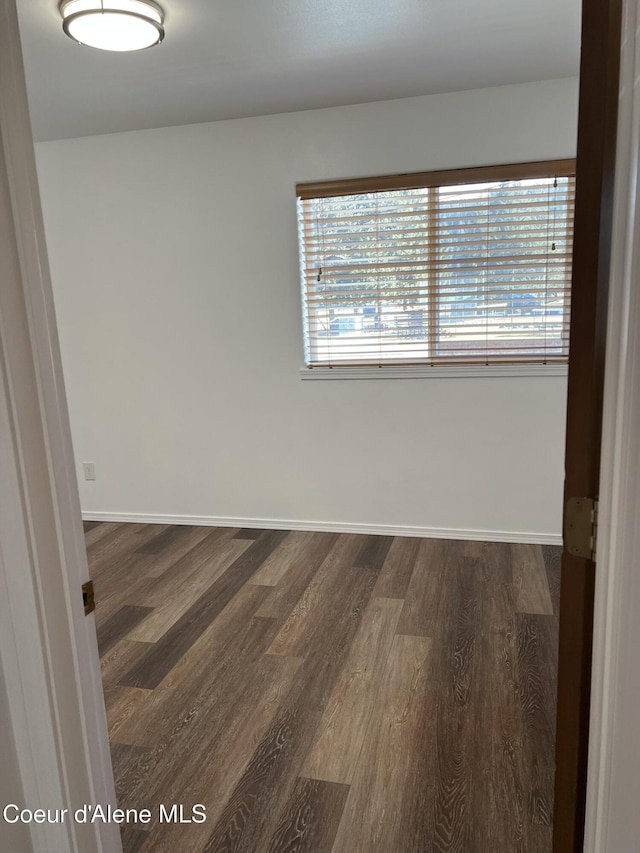 spare room featuring dark wood-style flooring and baseboards