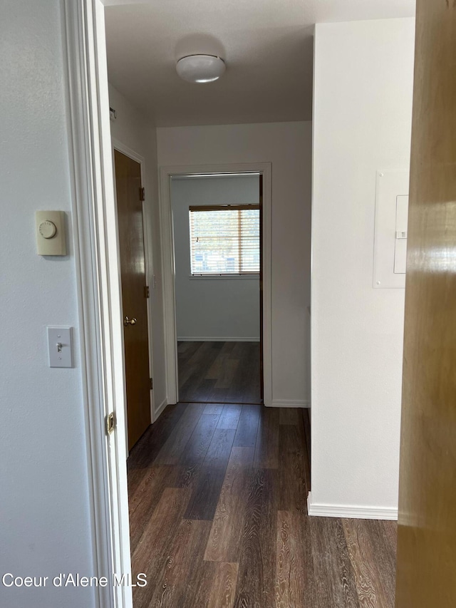hallway with dark wood-type flooring and baseboards