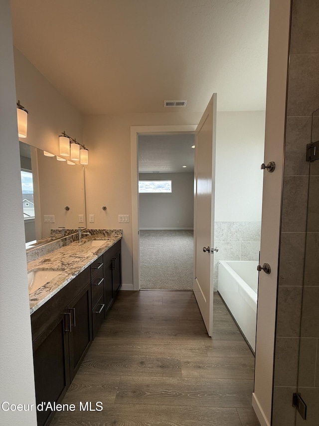 3402 N Cyprus Fox Loop, Post Falls, ID 83854 - full bathroom featuring double vanity, wood finished floors, a tub, and french doors