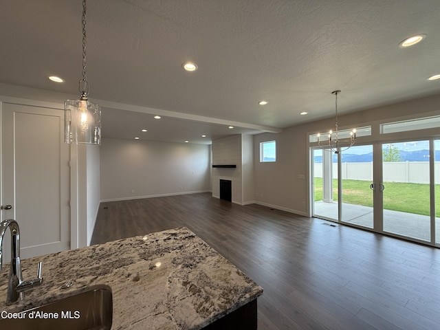 3402 N Cyprus Fox Loop, Post Falls, ID 83854 - unfurnished living room with a large fireplace, recessed lighting, dark wood-style floors, a textured ceiling, and a chandelier