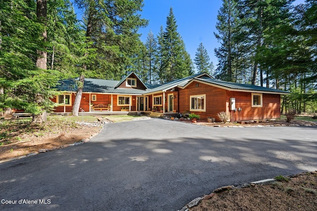 view of front of property featuring a standing seam roof, covered porch, metal roof, and driveway