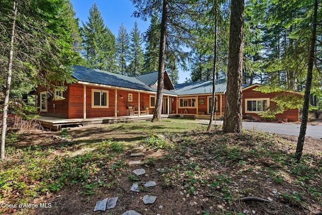 view of front facade with metal roof, a wooden deck, and aphalt driveway