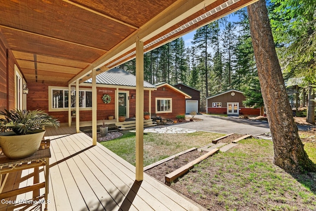 wooden deck with concrete driveway, a garage, an outdoor structure, and a lawn