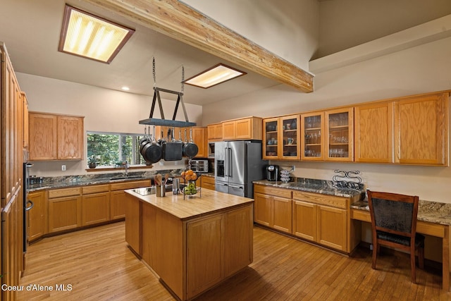 kitchen featuring butcher block countertops, high end fridge, light wood-style flooring, a kitchen island, and a sink